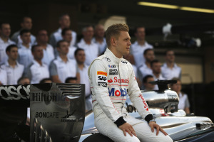 Kevin Magnussen sits on the car during a team photo session.