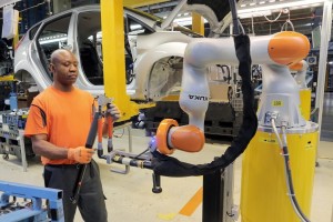 Car Workers and Mini Robots Work Hand in Hand